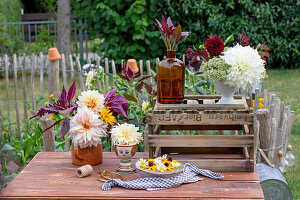 Flower arrangement with dahlias, rudbeckia and daisies on garden table