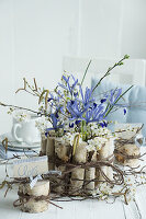 Irises with birch twigs and plum blossoms as a bouquet in a birch branch vase
