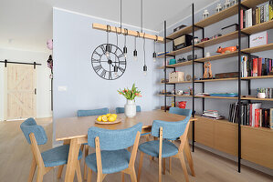 Dining area with blue chairs in front of floor-to-ceiling shelves