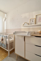 Chest of drawers with changing mat and cot in the children's room