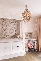 White four-poster bed with bird wallpaper and small writing desk in the girls' room in shades of pink