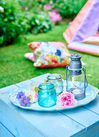 Glass vases and lantern on wooden table in summer garden