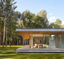 Flat-roofed house with open sliding doors, surrounded by the forest