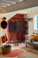 Metallgitter-Kleiderschrank in Ecke eines Wohnraums mit Katze auf Sofa und gemustertem Teppich