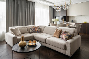 Upholstered sofa in cool beige in open Hampton-style living room, dark brown color palette with gold accents
