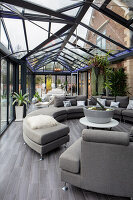 Conservatory with glass roof, modern furniture and plant decoration