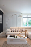 Modern eingerichtetes Wohnzimmer mit weißem Sofa, Bogenlampe und keltischer Harfe