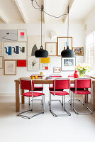 Dining area with table, red chairs and picture wall