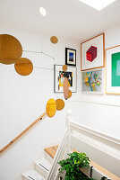 Mobile above staircase with framed pictures on white wall