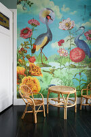 Colorful wall design with flora and fauna, rattan furniture and a dark wooden floor