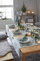 Festively laid dining table with light blue accents and candlelight in winter