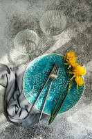 Minimalist table decoration with turquoise blue plate and daffodils