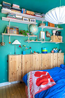 Open shelves, including narrow wooden cupboard in bedroom with blue wall