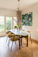 Marmer dining table with yellow chairs and tropical mural