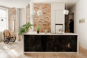 Modern kitchen island with black front and brick wall in the background