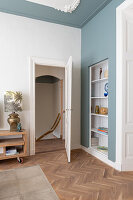 Room with herringbone parquet flooring and white built-in shelving