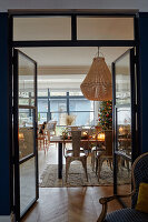 View through open glass doors into the dining room with a Christmas table and pearl lamp above it