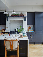 Blue cupboards and center island with marble elements in Victorian kitchen