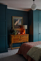Antique chest of drawers in front of a dark-colored wall, flanked by matching wardrobes in the bedroom