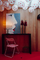 Weiße Lampions mit roten Punkten, roter Klappstuhl mit weißen Punkten, Wohnraumgestaltung mit Kunstwerk