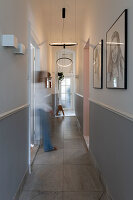 Hallway with modern ring pendant lights and framed drawings on the wall