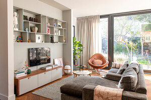 Bright living room, shelving wall, corner sofa and brown leather armchair