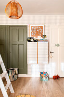 Children's room with green cupboards, patterned wallpaper and toys