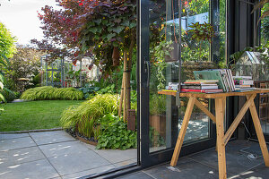 Blick auf einen modern gestalteten Garten durch offene Glastüren