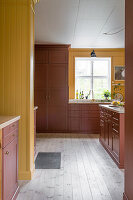 Yellow and red-brown kitchen with light-colored wooden floor