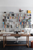 Wooden desk with iMac in front of a white bookshelf in a modern study