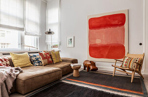 Modernes Wohnzimmer mit braunem Sofa, bunten Kissen und großem roten Wandbild