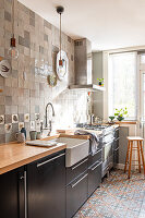 Tiled kitchen with black cabinets and wooden worktop