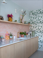 Modern kitchen with pink patterned tiles and floral wallpaper