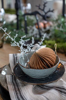 Paper ornament and white twigs in ceramic bowl on striped cloth napkin