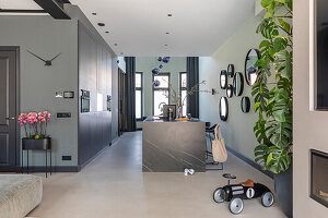 Modern open-plan kitchen with black island and round mirrors on the wall