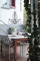 Tisch und Stühle mit maritimen Kissen, Leuchter und Rankpflanze auf der Terrasse