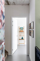 Hallway with graphic wallpaper with view into room with decorative ladder