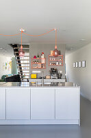 Modern kitchen with light-colored cupboards and pink pendant lights