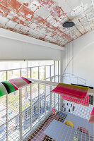 Gallery room with net, colorful cushions and light installation on the ceiling