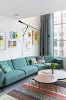 Green corner sofa in modern living room with pictures and round coffee tables