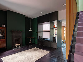 Living room with dark green walls, fireplace and central room divider