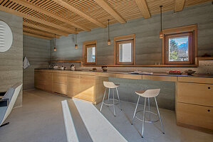 Modern kitchen with concrete walls and wooden elements, mountain view through window