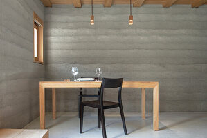 Minimalist dining area with concrete wall and wooden furniture
