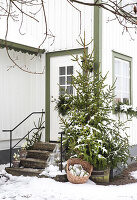 Snow-covered house entrance with fir tree and winter decorations