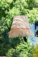 Hanging raffia lamp in the summer garden