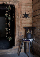 Rustic corner of a wooden hut with a garland of pine cones, twigs and golden acorns, black star on the wall