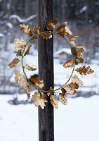 Golden wreath of leaves on wooden posts against a wintry backdrop