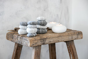 Stacked, painted pebbles and tea lights on a rustic wooden stool