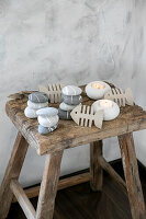 Decorative arrangement of painted stones, cardboard fish and candles on a rustic wooden stool