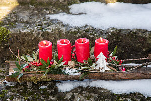 Advent arrangement with red candles and Christmas decorations in the snow